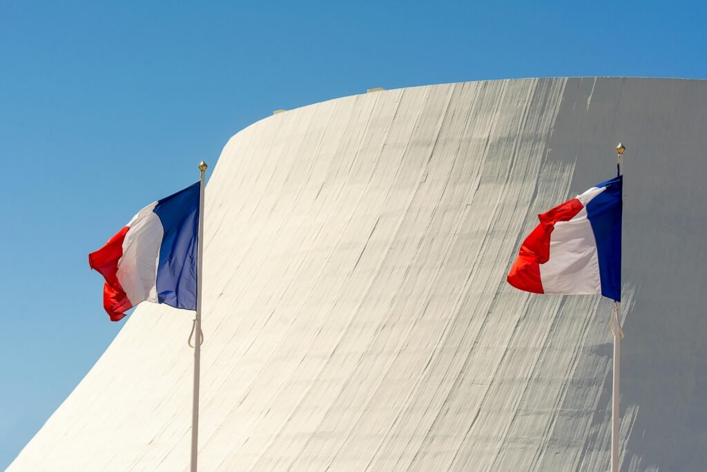 Two French flags waving in front of modern architecture in Le Havre, France.
