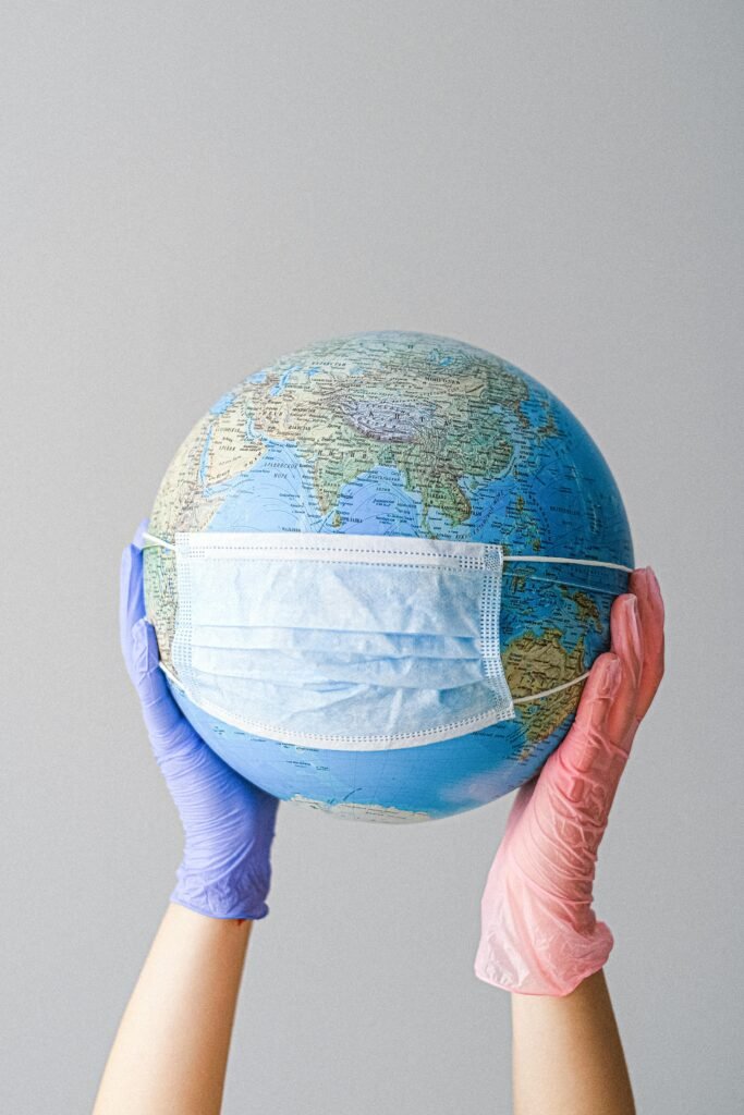 Hands in gloves holding a globe with a mask, symbolizing global health and pandemic protection.